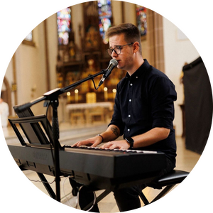 Musiker Sebastian Tribwoski singend mit einem Klavier